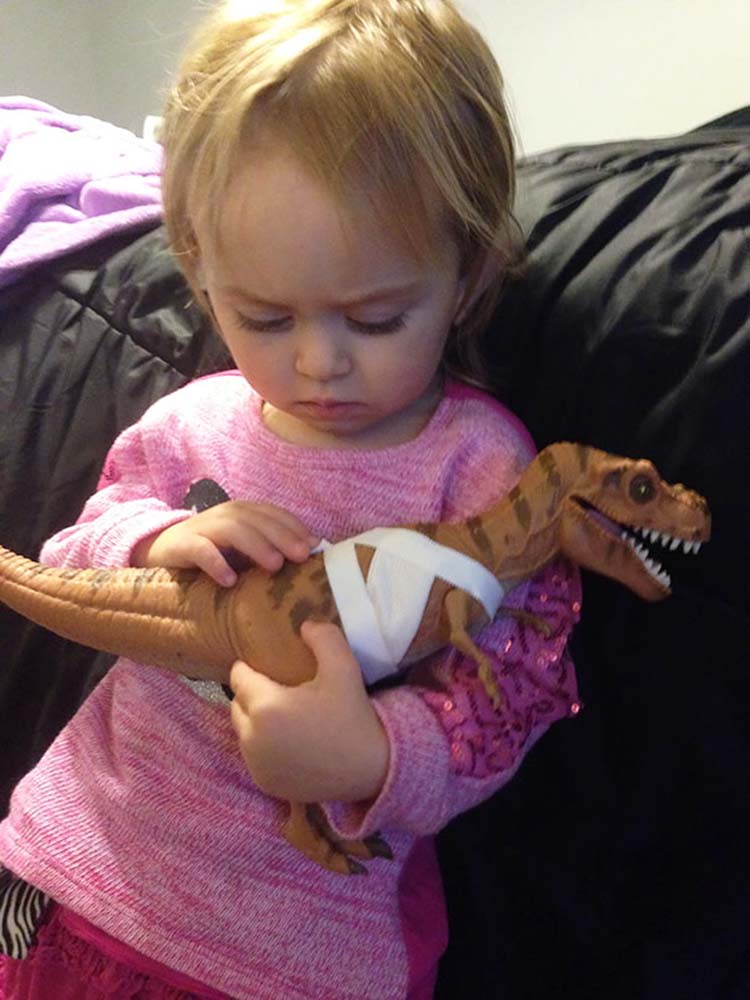 Niña consuela a un dinosaurio de juguete Niña consuela a un dinosaurio de juguete