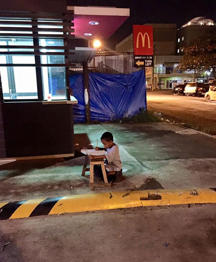 Niño indigente haciendo sus tareas Niño indigente haciendo sus tareas