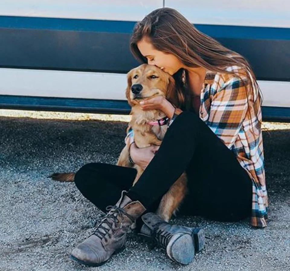 Mujer y su perrita sentadas fuera de furgoneta