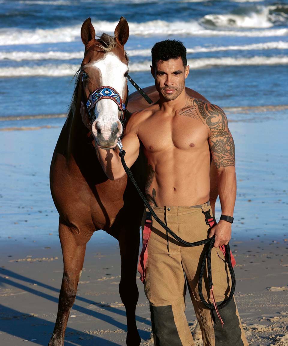 Bombero en la playa junto a caballo