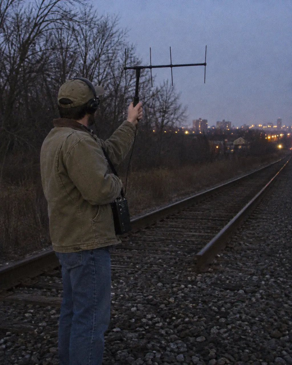 Miles de coyotes viven entre la gente de Chicago y casi nadie los ve 4 Persona de campo con una antena de telemetría en forma de H, al atardecer, junto a unas vías del tren al borde de un bosque