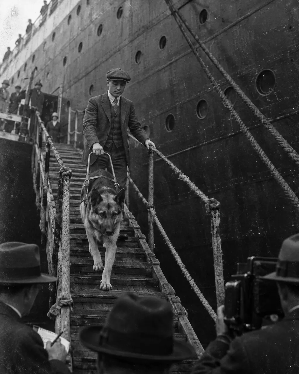 Nueva York, 1928: un periodista retó a un joven ciego a cruzar una avenida con su pastora alemana 4 Casco remachado de un trasatlántico negro que llena casi todo el encuadre, visto desde abajo en un muelle de madera, con ojos de buey y cabos de amarre inclinados